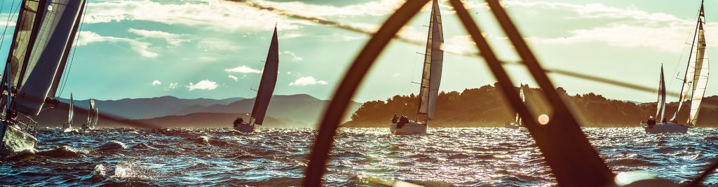 Sailboats on choppy water with hills in the background on a sunny day