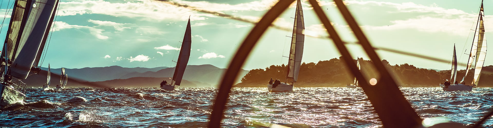 Sailboats on choppy water with hills in the background on a sunny day