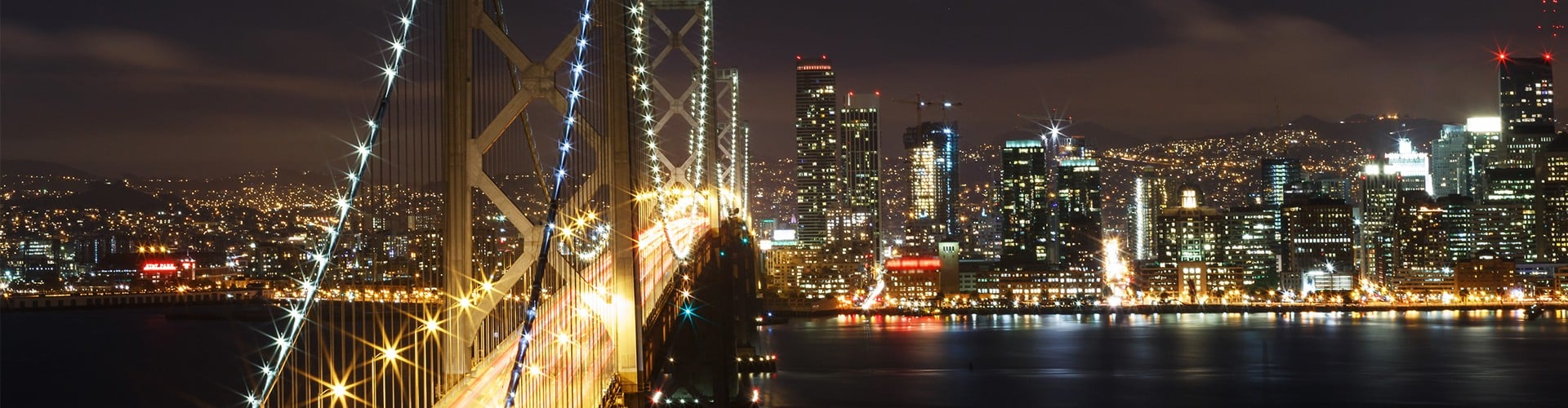Downtown San Francisco bridge lit up at night with cityscape in the background