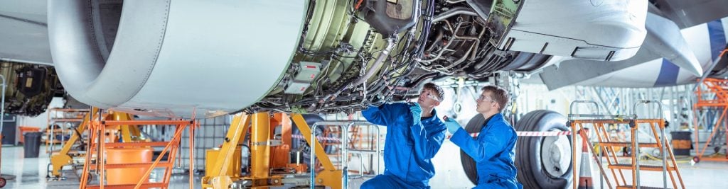 Two young men working on the fuselage of an airplane