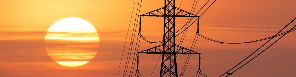 Electrical pylon against red sky at sunset
